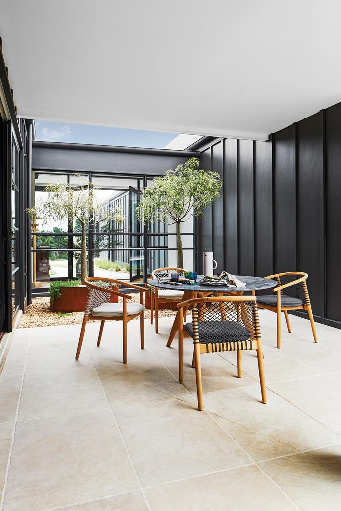 A table and chairs from [Cosh Living](https://coshliving.com.au/|target="_blank"|rel="nofollow") are a great match for the home's black-metal window frames and external wall panels. Cloth napkins from [Greenhouse Interiors](https://greenhouseinteriors.com.au/|target="_blank"|rel="nofollow").