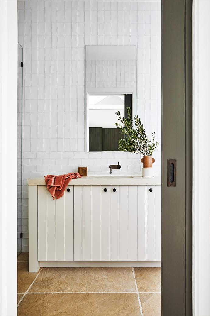 Hand-glazed wall tiles bounce light around the bathroom and look great with the country-style cabinetry. Vessel, Established For Design. Towel, Kobn.