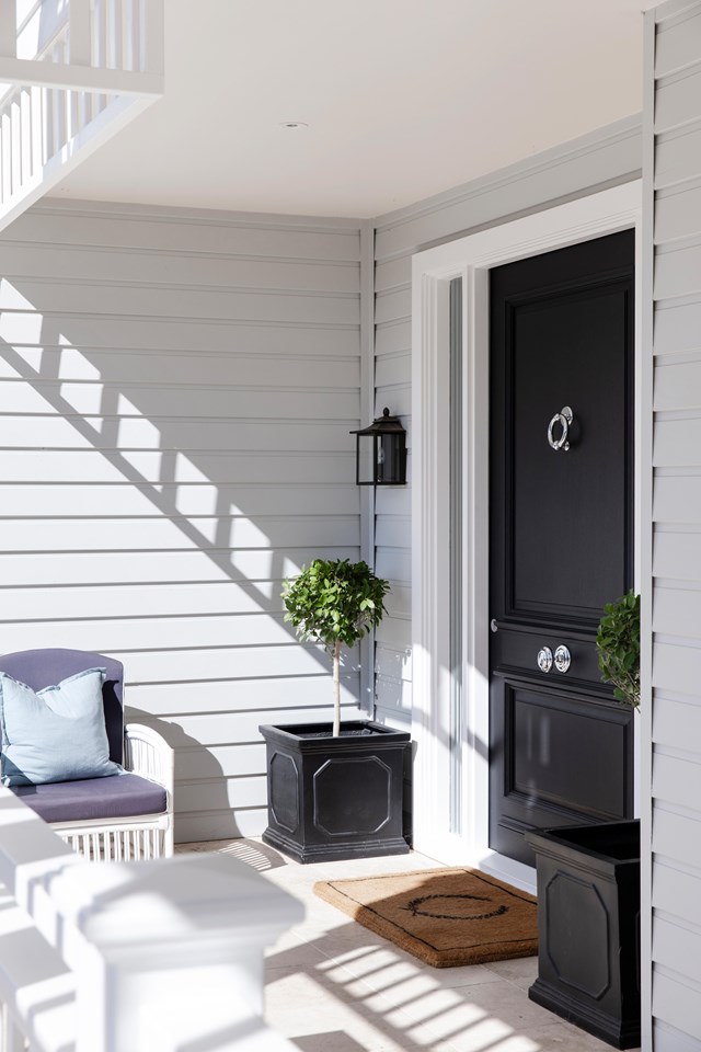 Soft grey weatherboards surround the entrance to [this renovated Hamptons-style home](https://www.homestolove.com.au/gracious-hamptons-home-sydney-23521|target="_blank") in Sydney's north, punctuated by a black front door.