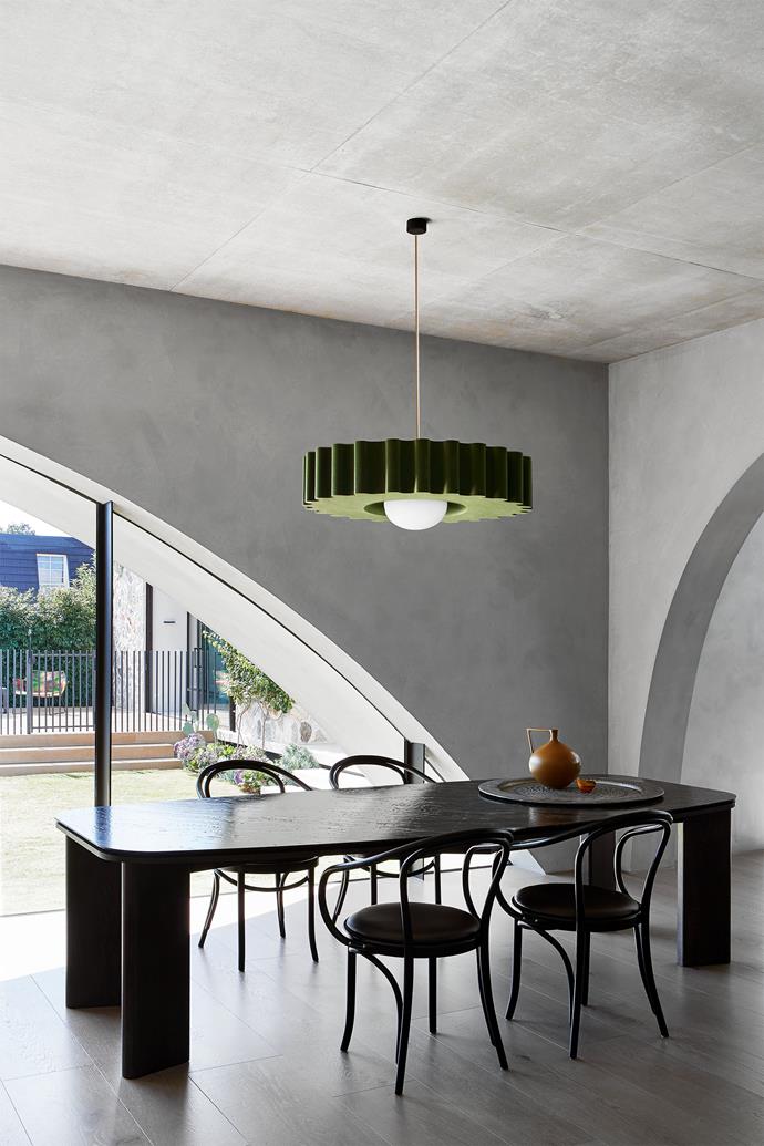 In the dining area, a 'Rook' dining table by Studio Acustico with dark oak legs and a marble top is paired with Thonet 'B9' bentwood dining chairs. Hanging above is a khaki 'Musica II Opera' pendant light by Acustico Lighting which aids in noise absorption.