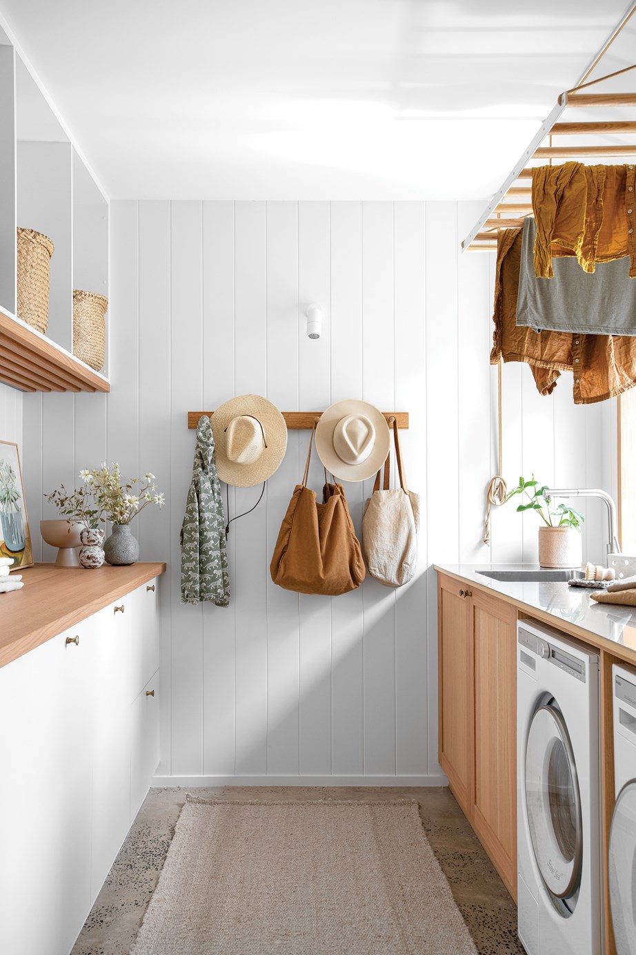 The laundry in this [low-tox, sustainable home](https://www.homestolove.com.au/sustainable-home-byron-hinterland-23565|target="_blank"), features a functional galley layout and a mix of clever (and stylish!) storage solutions, from wall hooks to a suspended clothes drying rack.