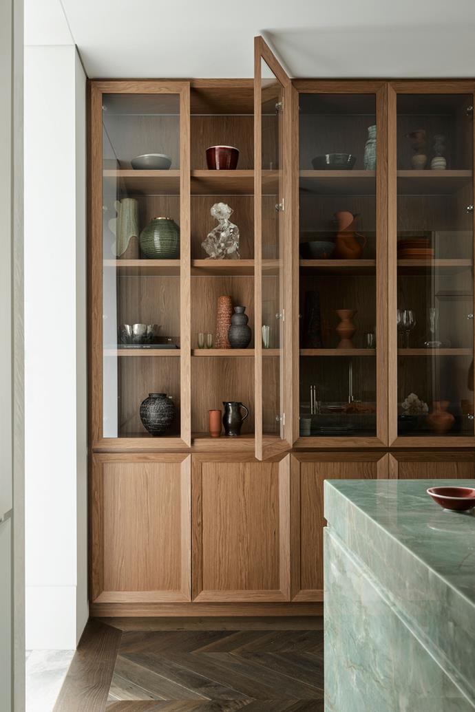 A custom cabinet with glass doors allows the owners to showcase art and photos. The timber is TrueGrain Pinecone by Briggs Veneers and was chosen to complement the herringbone floor in Otta by Tongue in Groove. Vessels and bowls from The Dea Store, Utopia Art Sydney, Palmer and Penn, Tania Rolland, Top 3 By Design, Ignem Terrae Ceramics and Saint Cloche.