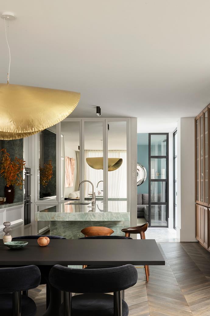 A playful Gervasoni Brass 96 pendant light from Anibou hangs over a Holo Dining Table from Fanuli. Dining Room Chairs by Tom Dixon, marble bowl by Greg Natale, sculptures from Saint Cloche.