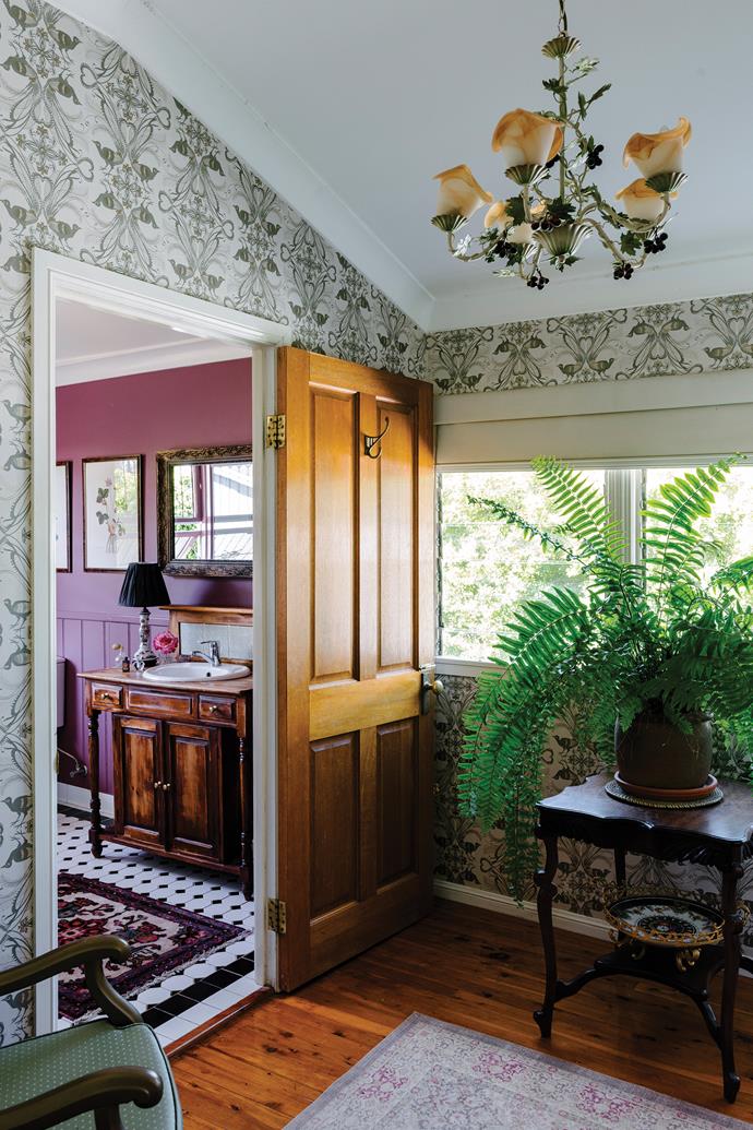 The sunroom of florist [Leah Stirton's charming homestead](https://www.homestolove.com.au/charming-homestead-emerald-23704|target="_blank") is adorned with wallpaper by Catherine Martin. Beyond, a rich burgundy red bathroom beckons. The beautiful botanical light fitting is one of the room's best features, an object that was found by Leah's mother at Townsville Restoration and Lighting. "One of my girls used to say, 'Why is our house so old? I just want a new house that's all-white'," says Leah. "Oh God! You've got no idea how much I hate all-white."