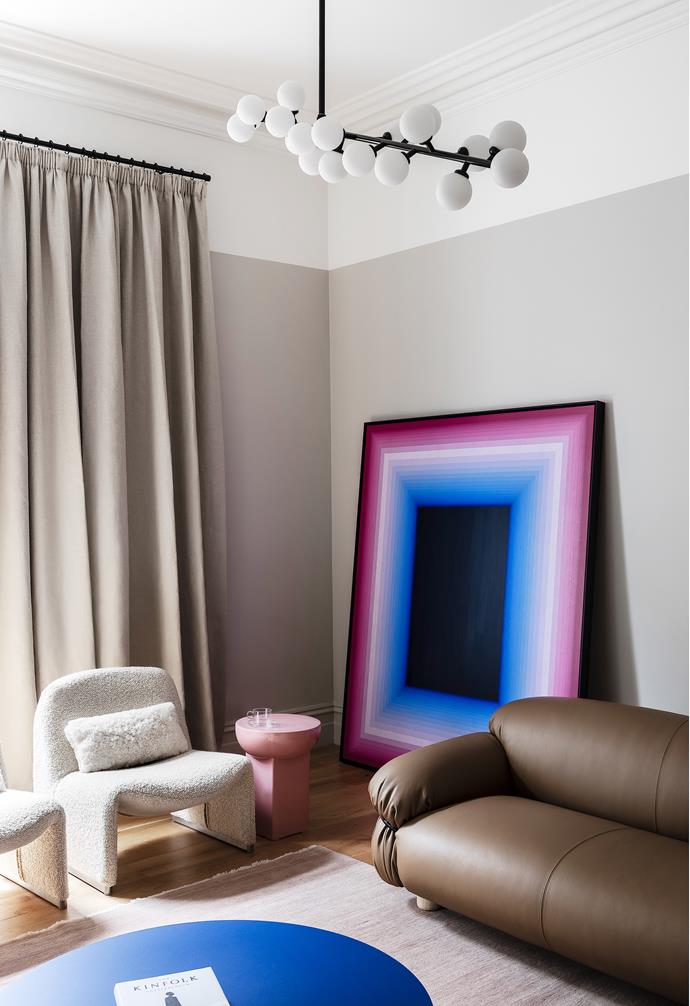 In the living room, boucle armchairs and a Tacchini 'Sesann' sofa were selected for their gentle yet sculptural forms that contrast with the linear architecture of the home. "The artwork really gives this room a huge hit of colour," says Cassie of the striking Andy Harwood piece leaning against the wall.