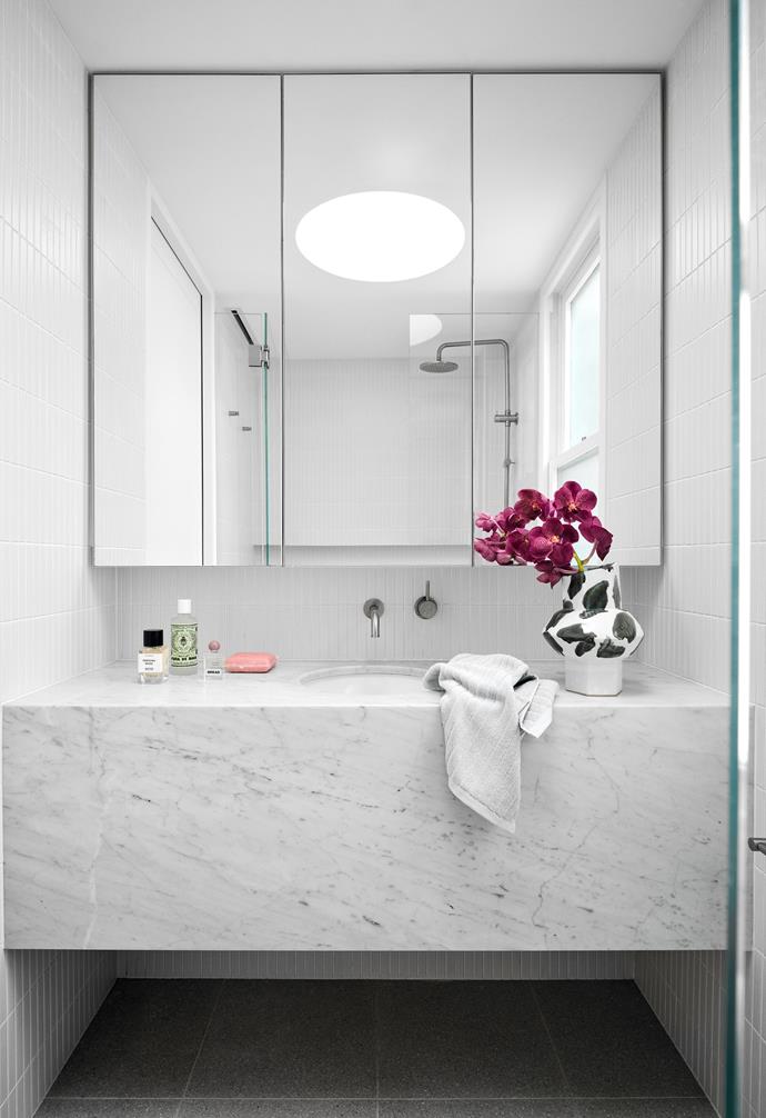 A minimalist marble vanity brings texture, depth and a little luxury to an otherwise all-white palette in the bathroom.