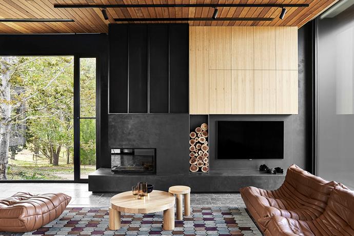 A 'D1000VAG Right Corner' fireplace from Chazelles Fireplaces has a concrete surround, poured in situ, with applied charcoal render, which is also used for the hearth and wall finish, and custom metal-framed cladding and inset mesh for ventilation.