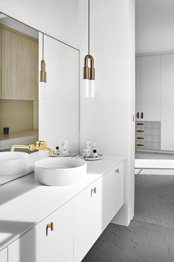 American oak timber veneer bathroom joinery by Gap Joinery is finished in Dulux 'Natural White', with a [Dekton benchtop](https://www.homestolove.com.au/durable-engineered-stone-kitchen-benchtops-18823|target="_blank") in Halo from Cosentino. Studio Bagno 'Shard X Circle' basin in Gloss White and Brodware 'Halo' wall mixer in brushed europlate, both from Routleys. 'T Pull' door handles in Brass from Lo & Co. I-O-N 'N' pendant light from Porcelain Bear. Tonalite 'Geomat' porcelain floor tiles in Warm Grey from Academy Tiles.