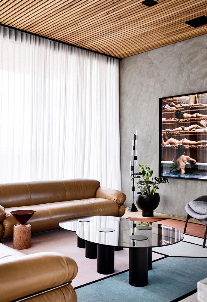 The warm timber ceiling detail, complemented with similar tones in the artwork, rug and leather sofas bright together the living room in [this sophisticated penthouse apartment](https://www.homestolove.com.au/a-sophisticated-entertainers-penthouse-in-brighton-18857|target="_blank") in Brighton.