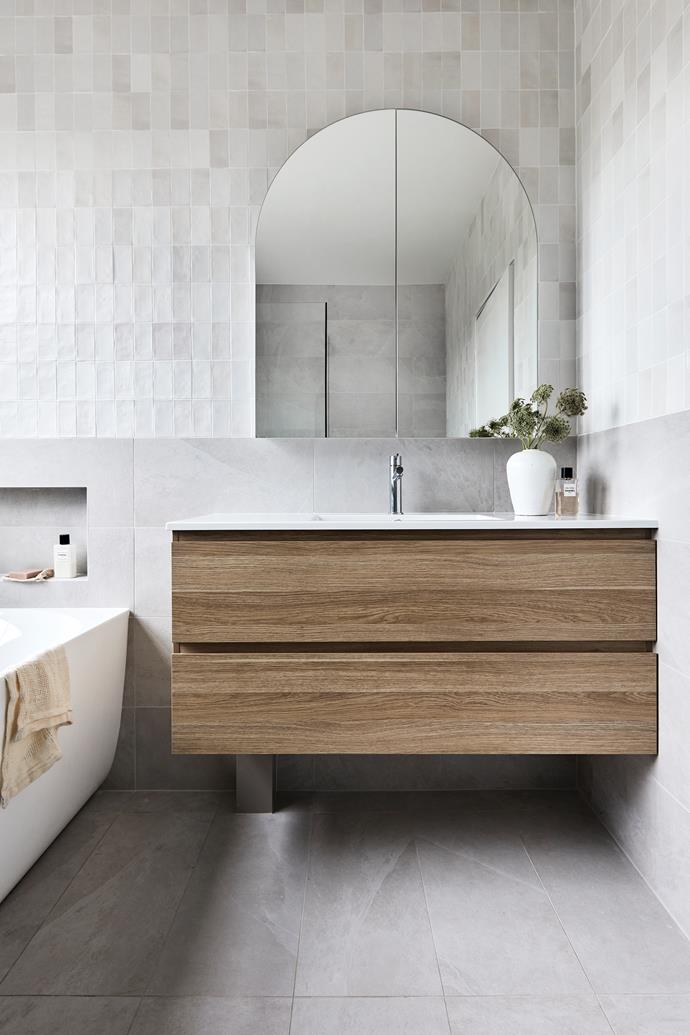 Handmade Fez white gloss wall tiles from [Di Lorenzo](https://dilorenzo.com.au/|target="_blank"|rel="nofollow") create a beautiful backdrop. Bianco Naturale floor tiles by Eureka Stone, also from [Di Lorenzo](https://dilorenzo.com.au/|target="_blank"|rel="nofollow"). Bathroom Life vanity in [Laminex](https://www.laminex.com.au/|target="_blank"|rel="nofollow") Classic Oak with solid surface white benchtop, Kado Neue Arch mirror and Posh Solus back-to-corner freestanding bath, all from [Reece](https://www.reece.com.au/|target="_blank"|rel="nofollow"). Towel, [Eadie Lifestyle](https://www.eadielifestyle.com.au/|target="_blank"|rel="nofollow").