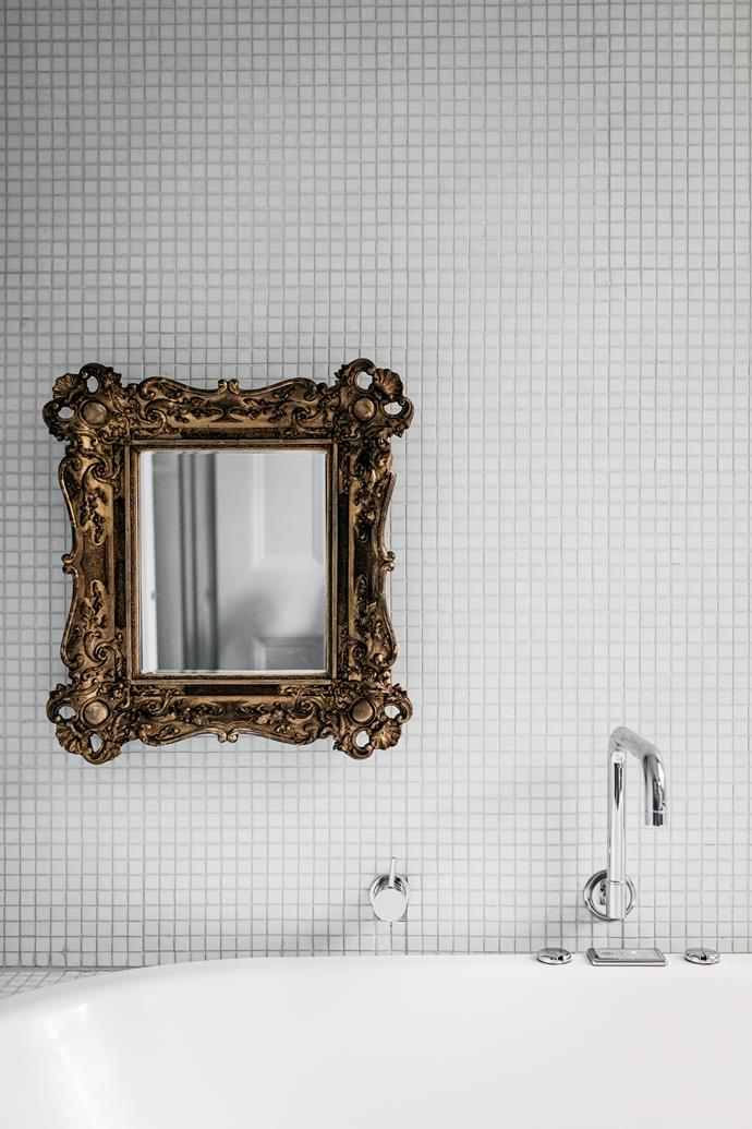A gilt-framed mirror above the bath adds a baroque touch.