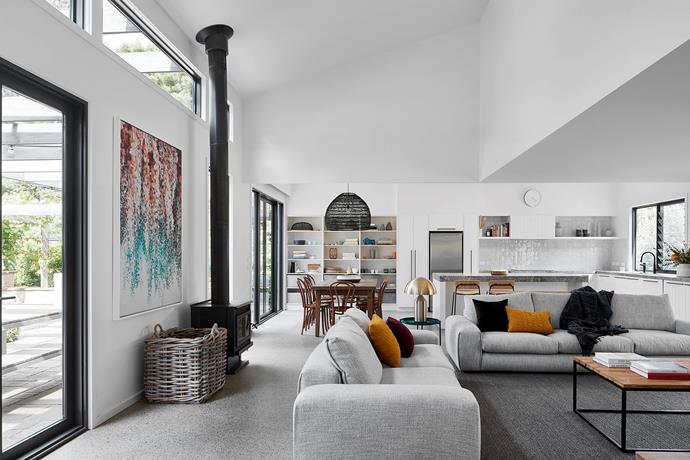 A relaxed, open living area and entertainment space with sofas from Jardan is bathed in light from clerestory windows and airy angled ceilings. Artwork by unknown artist. Dining chairs from Thonet. 'Wicker Ball' pendant light from House of Orange. Oluce 'Atollo' table lamp from Euroluce.