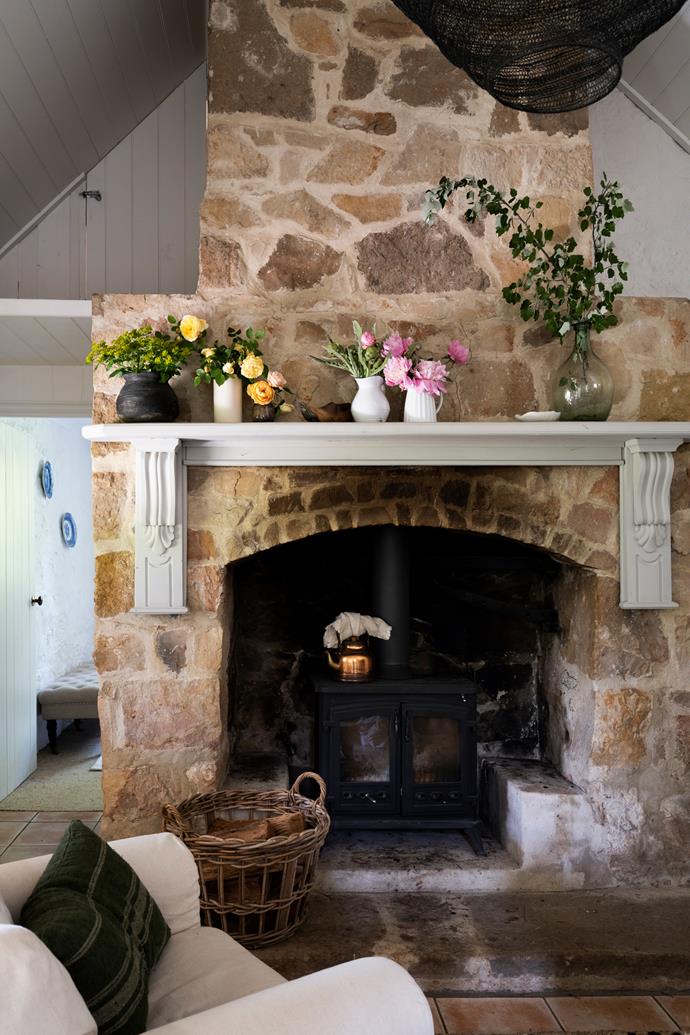A large original fireplace dominates the space. The couple installed a [Masport](https://www.masportheating.com.au/en-au|target="_blank"|rel="nofollow") 'Westcott' cast-iron wood heater. The original mantle above has been repainted Mezzie + Frank Docklands and holds vases of blooms from the garden, while a [Haven & Space](https://havenandspace.com.au/|target="_blank"|rel="nofollow") basket is topped up frequently with firewood.