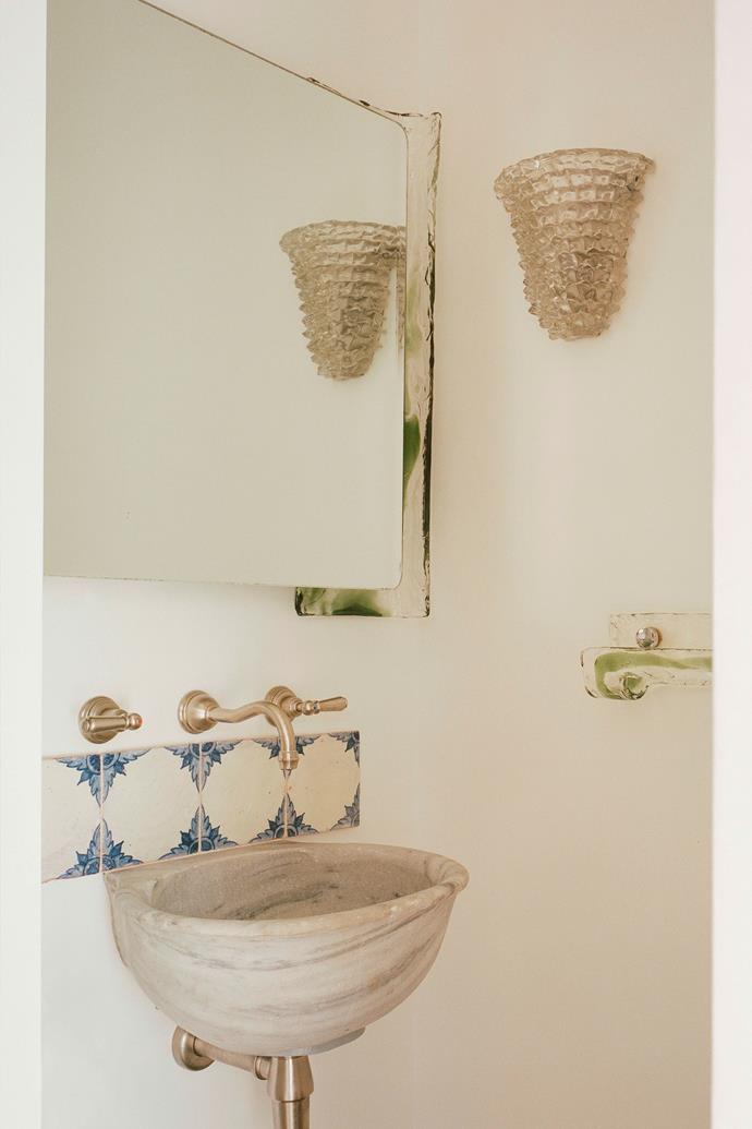 In the ensuite, a wall sconce, green and clear glass, and a '60s backlit mirror are all Murano. The antique Greek washbasin and artisan tiles are from Lucca.