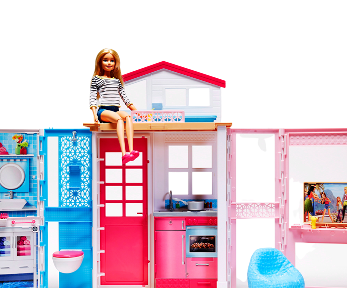 Barbie doll sitting atop a toy Barbie home