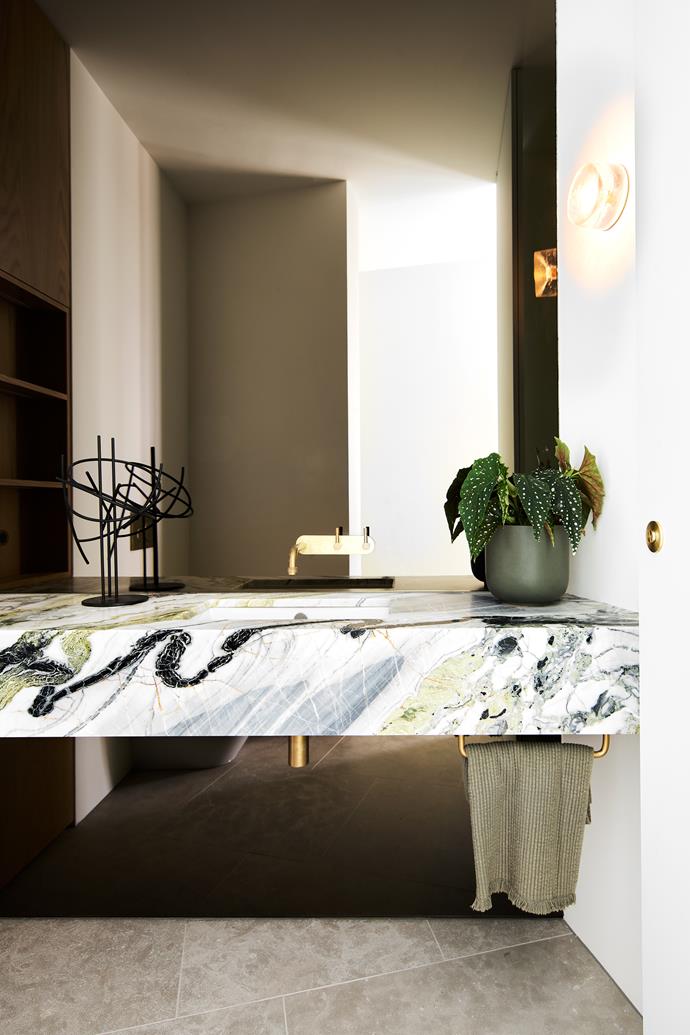 In the powder room, benchtop in Mint Ice marble from Euro Marble. Yokato tapware in tumbled organic brass from Brodware. Evolution sculpture by Dion Horstmans. 'Anton' mini wall sconce from Volker Haug.