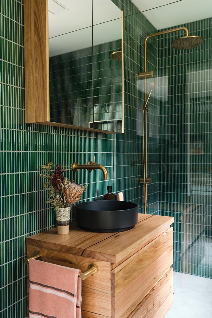 'The Bush' bathroom features a stunning selection of deep green finger tiles paired with natural timber and brass hardware.
