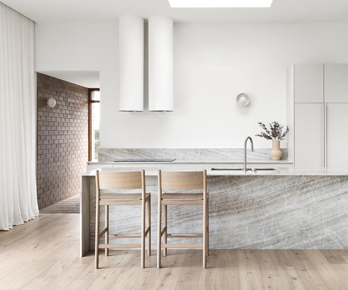 The kitchen island, splashback and benchtops are formed from rugged-looking 'Taj Mahal' quartzite from [CDK Stone](https://www.cdkstone.com.au/|target="_blank"); the waterfall edges of the island give a sense of movement. The 'Gus' barstools are from [Jardan](https://www.jardan.com.au/|target="_blank"). The Lucciola wall light from [Lights Lights Lights](https://www.lightslightslights.com.au/|target="_blank") is a simple design that adds to the soft brightness of this minimalist, modern country kitchen.