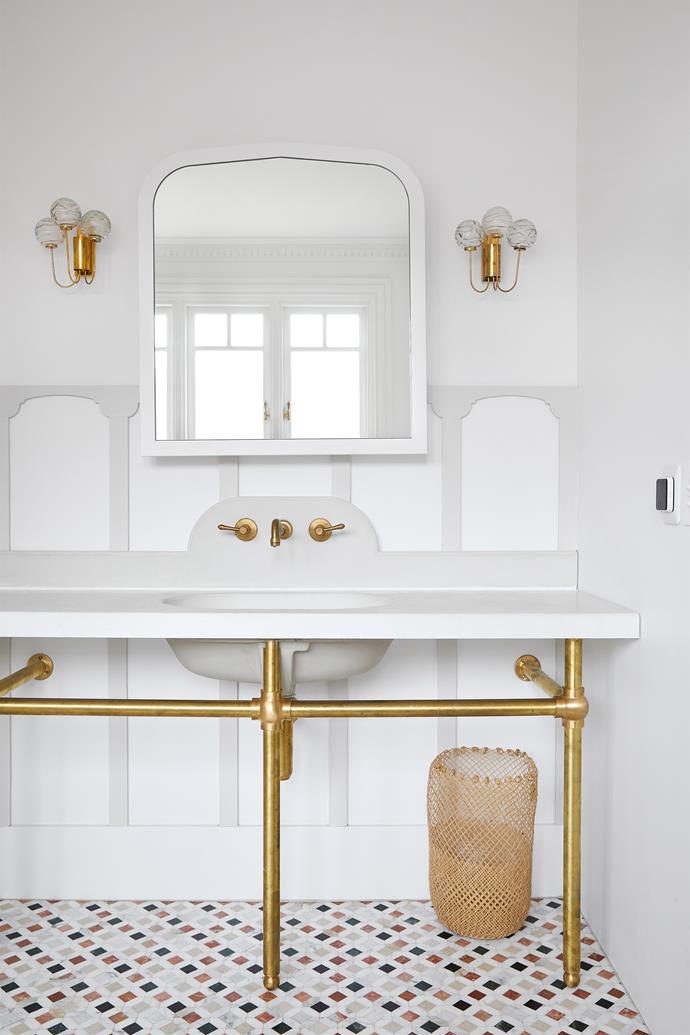 Understated and graceful, the bathroom of [this Coogee home](https://www.homestolove.com.au/olli-ella-bundock-house-south-coogee-24366|target="_blank") features marble mosaic tiles underfoot, an incredibly elegant vanity (under which sits a basket from Olli Ella) and ornate brass vintage sconces.