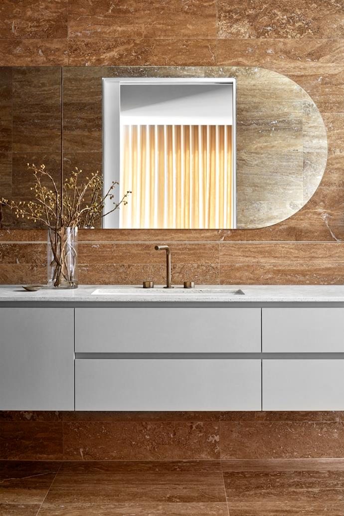 Noce Eschilo travertine lines the walls and floor of this sleek [70s-and-Greek-design-inspired home](https://www.homestolove.com.au/state-of-kin-house-tour-24778|target="_blank") in Perth, WA. Above the bath, a circular skylight lets in an abundance of light.