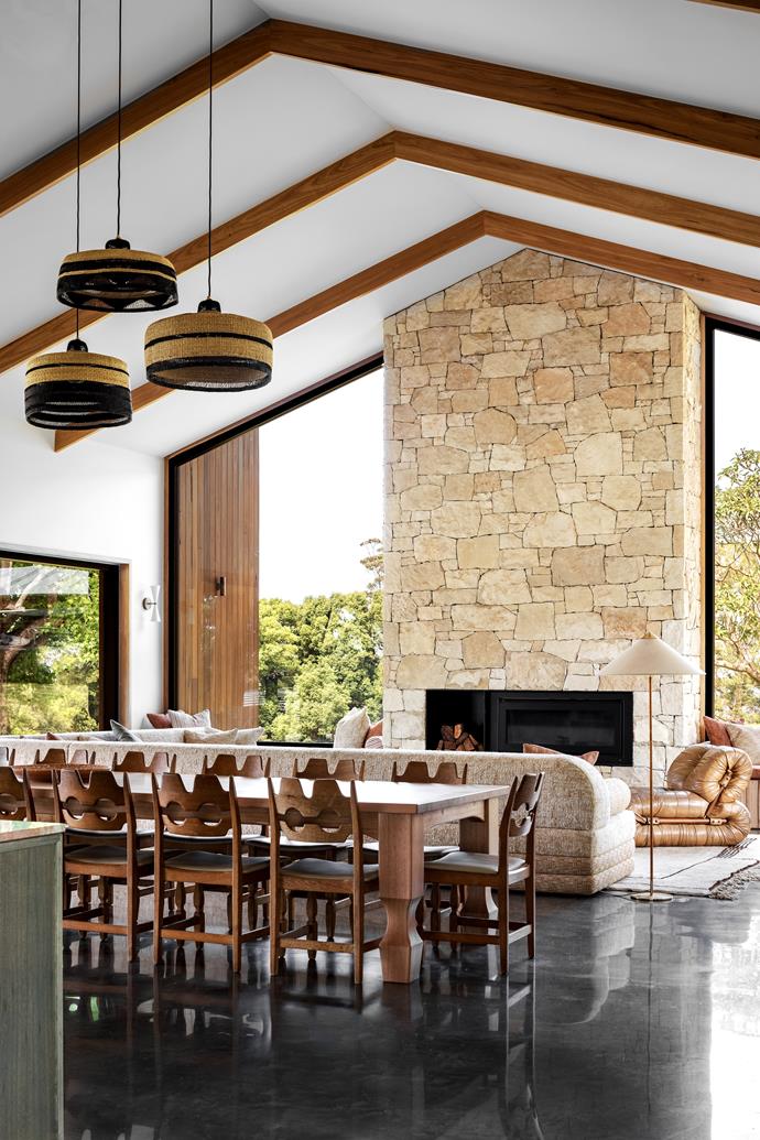 A stacked stone fireplace is flanked by two full-height glass windows in this [tropical Byron Bay barn-style home](https://www.homestolove.com.au/tropical-byron-bay-barn-house-24795|target="_blank"). Elsewhere, a bright and airy glass walkway connects two zones of the home.