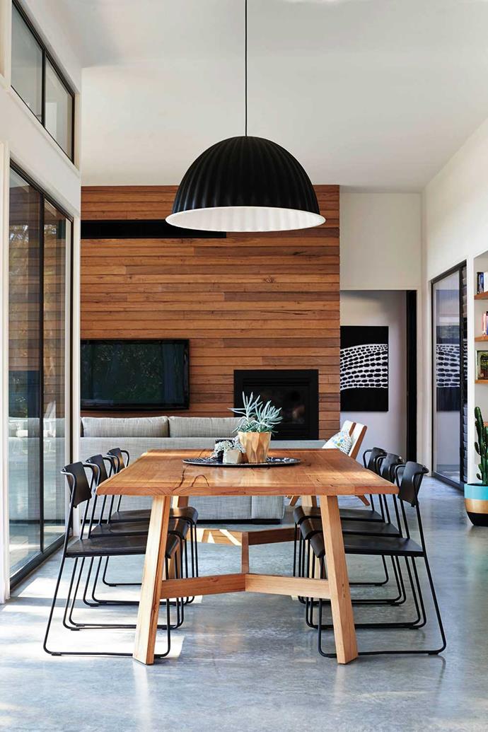 A timber feature wall helps the timber dining table to tie in to this monochrome living and dining space. *Photographer: Nikole Ramsay*