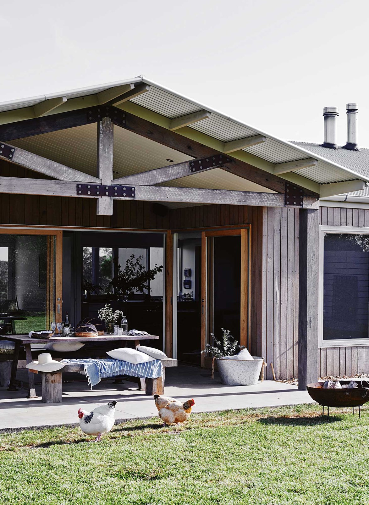 Reclaimed timber frames an impressive back verandah at a [newly built home in Freshwater creek](https://www.homestolove.com.au/designer-dream-home-in-freshwater-creek-victoria-13657|target="_blank"). A brood of chooks scan the lawn for signs of food. *Photo: Lisa Cohen / Stylist: Tess Newman-Morris*