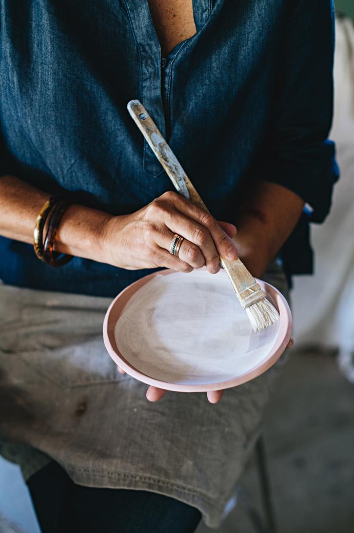 When a piece calls for a more refined touch, Anna applies a porcelain glaze. She brushes glaze onto a greenware bowl before it enters the kiln for firing.