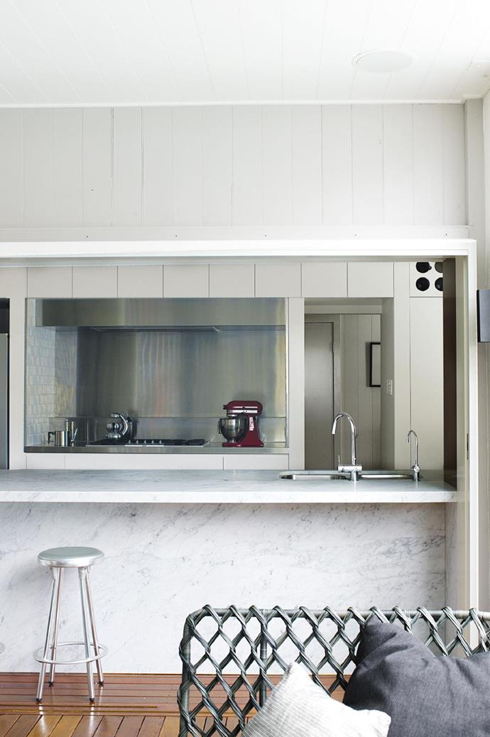 Cool white marble and stainless steel create a sleek look that also offers a serene feel in the open-plan kitchen.