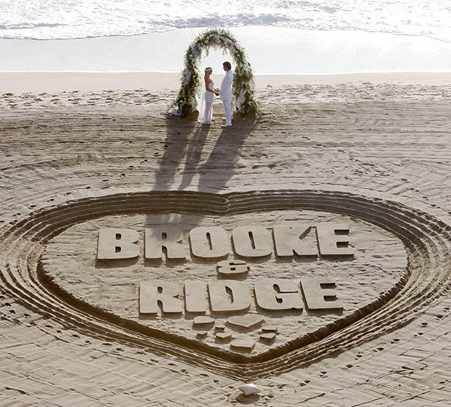 a scene from B&B with brooke and ridge carved on sand at a beach wedding