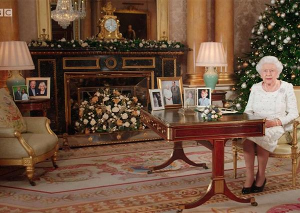In the far left background, The Queen has a framed photo of Harry and Meghan next to a portrait of Prince Charles and Duchess Camilla.