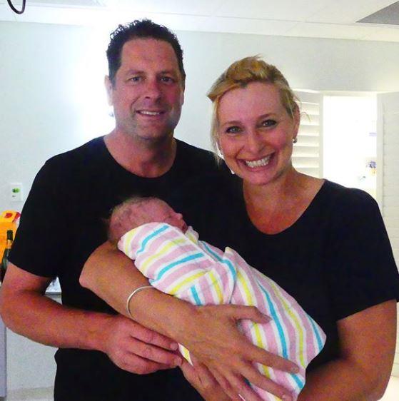 Joh, pictured with her husband, Todd Huggins, holding their grandson.