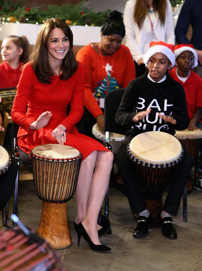 Kate takes part in some drumming 'music therapy' as she attends the Anna Freud Centre Family School Christmas Party at Anna Freud Centre on the 15 December, 2015 in London, England, in the same red Alexander McQueen number.