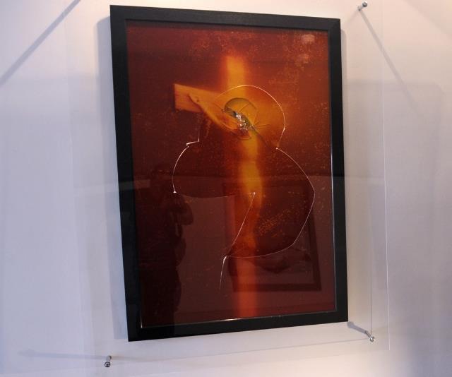 The controversial 1987 artwork "Piss Christ" by Andres Serrano, which continues to incite international uproar and is subject to ongoing vandalism (pictured here smashed by protestor in 2011). *(Source: Getty Images)*