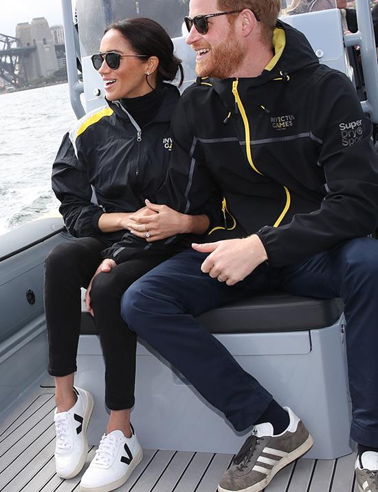 The dressed-down Duchess! On the same day, the 37-year-old wrapped up in an Invictus Games jacket and skinny-leg black jeans as she joined Harry on the water. She also switched her heels for Veja Project sneakers and her go-to KREWE sunnies. *(Image: Getty Images)*