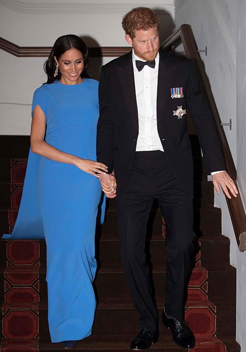 Ending their first day in Fiji on Tuesday, the royal couple stepped out looking classy as ever for an evening Soiree held by the Fijian Prime Minister. Meghan wore a striking blue SAFiYAA 'Ginkgo' cape gown for the event. *(Image: Getty Images)*
