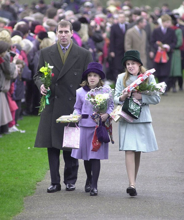 Interacting with royal fans walking to and from Christmas service is an annual tradition for the royal family. This particular year in 1999 Princess Eugenie and her sister were inundated with bouquets and presents. *(Image: Getty)*
