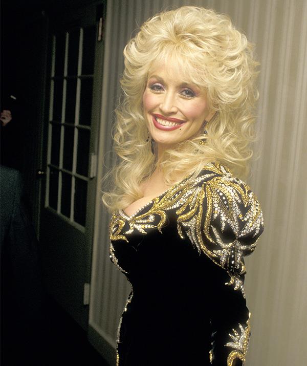 Pictured here in the 1980s, Parton embraced the bold trends of the decade in all its glory. *(Image: Getty)*