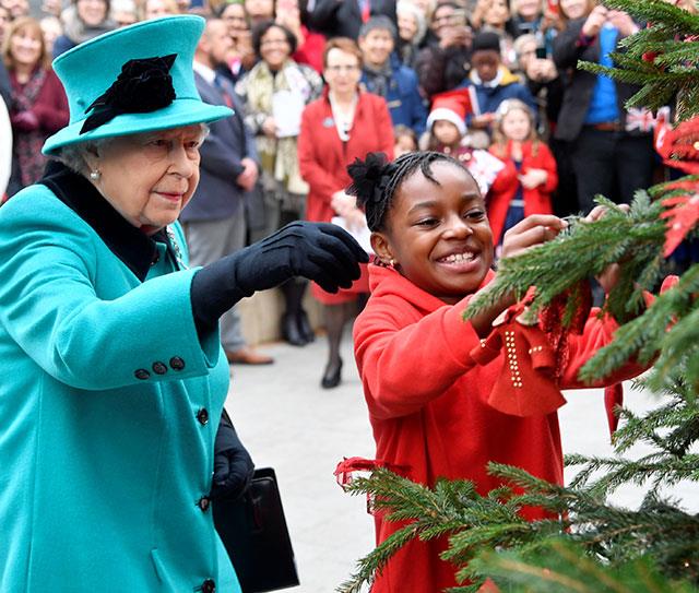 Imagine getting to decorate a Christmas tree with The Queen! That dream came true for eight-year-old Shylah Gordon when the pair hung baubles at the opening of Coram's new children's centre in London on December 5th. *(Image: Getty)*