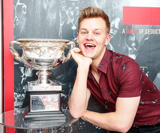 Comedian Joel Creasey gets up close and personal to the winner's cup at an Australian Open cocktail party. *(Image: Getty)*