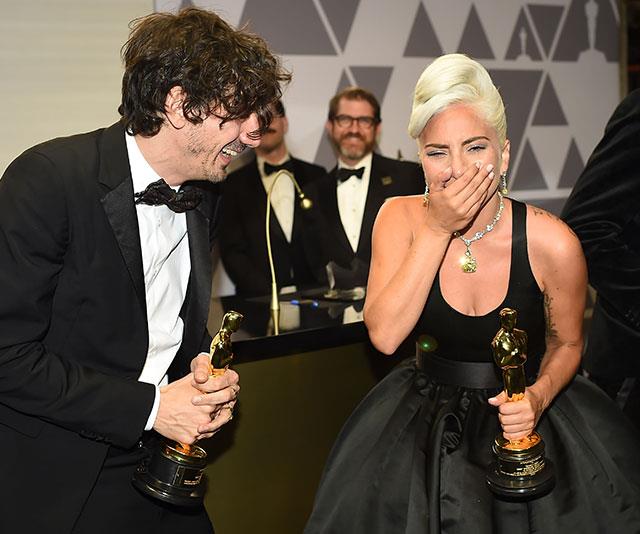 Still taking in her Best Song win, *A Star is Born* beauty Lady Gaga shares a laugh with Anthony Rossomando at the Governors ball at the Hollywood & Highland Center in LA. *(Image: Getty)*