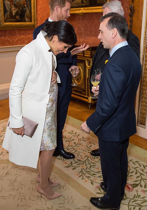 Check out that bump! Meghan paired the gorgeous dress with an old recycled favourite - her white Amanda Wakeley coat.
<br><br>
To finish it all off, Meghan accessorised with a dusty pink Wilbur and Gussie clutch and Paul Andrew pumps. *(Image: Getty Images)*