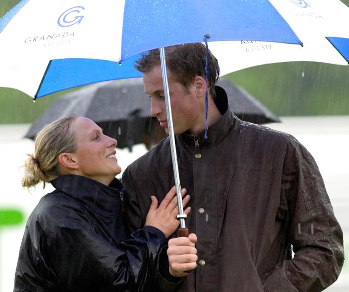 A dashing young Prince William keeping his cousin Zara Phillips dry during a particularly wet polo match in 2004. *(Image: Getty)*