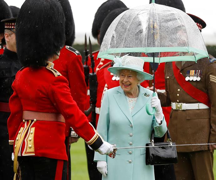 The Queen always holds her own umbrella. In fact, she's got a whole wardrobe full of them in different colours, to match all of her different outfits, just like this pretty mint one. *(Image: Getty)*