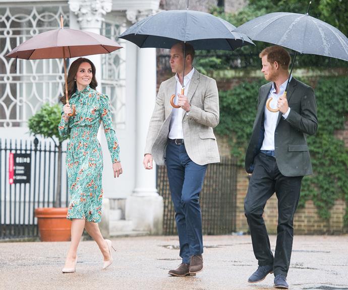 What a trio! Duchess Catherine, Prince William and Prince Harry pose for a photocall while casually strolling through the rain. *(Image: Getty)*