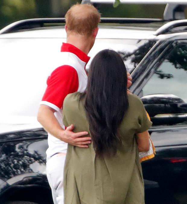 Prince Harry rubs Meghan's back as she and Archie support him during a polo match in July this year.