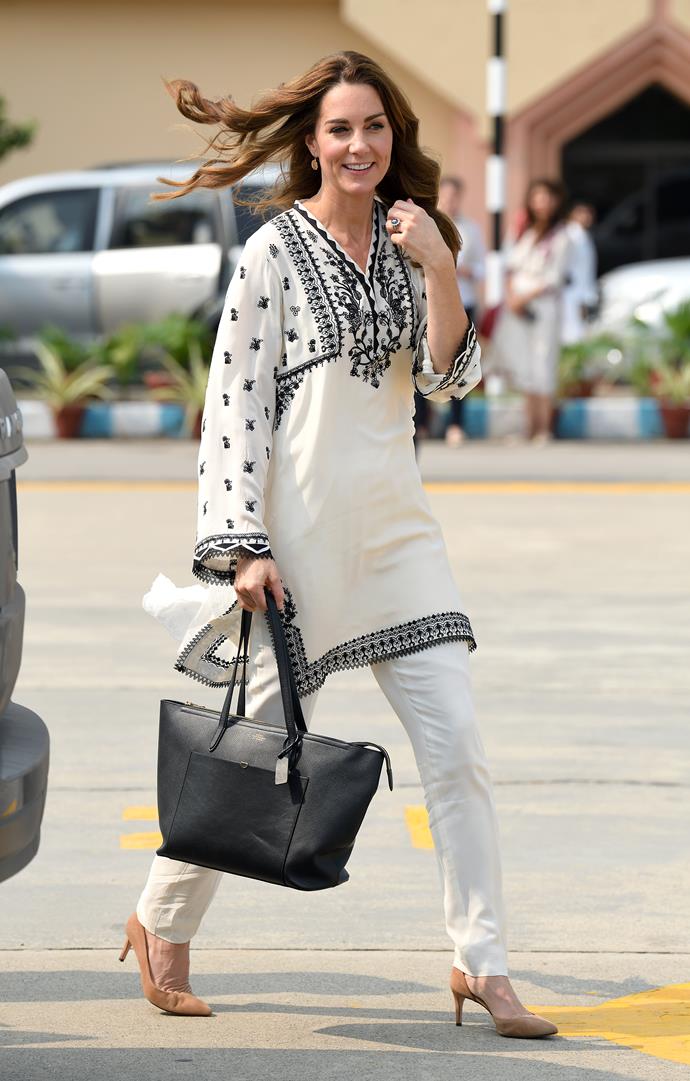 Earlier in the day, Kate was seen wearing a beautiful embroided tunic by Élan. She again wore her white Gul Ahmed trousers and added a pair of chic beige J.Crew heels. 
<br><br>
Finishing the look, the Duchess added a wide black tote bag by Smythson. We don't usually see royals carry bags of this size to their formal engagements, so it was refreshing to see Kate accessorise with something that we can take some major work-wear inspiration from!