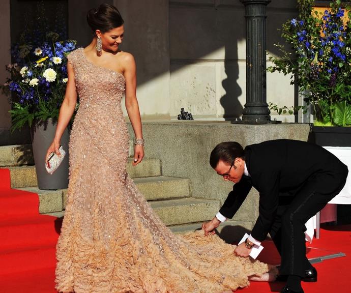 Prince Daniel helping his then-fiancee with her train at their pre-wedding dinner.