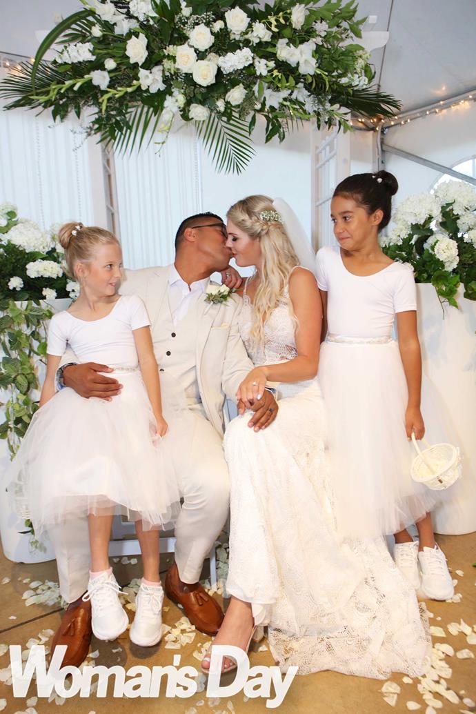 Their girls look on as their parents seal their new union with a kiss.