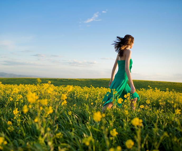 woman walking in a field of yellow flowers